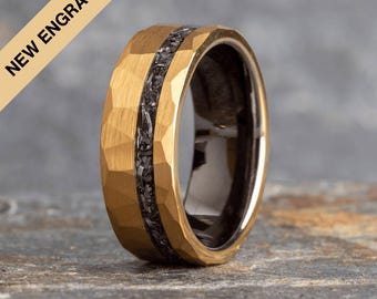 Op de afbeelding: Een gouden ring van wolframcarbide met een zwarte carbonfiber inlay. De ring heeft een gehammerde afwerking en een afgeschuinde rand.