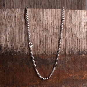 Könnte beinhalten: Eine silberne Kettenkette mit einem Karabinerverschluss.