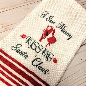 May include: White kitchen towel with red stripes and green embroidery that reads "I Saw Mommy Kissing Santa Claus". The embroidery also includes a red and white illustration of a couple kissing.