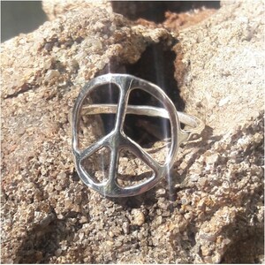 K&ouml;nnte beinhalten: Ein silberner Friedenszeichenring. Der Ring ist aus d&uuml;nnem Metall und hat ein schlichtes Design.