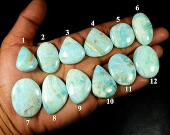 May include: Twelve polished gemstones in diverse shapes, such as teardrop, oval, and triangular. The stones exhibit a blend of light blue and green shades with delicate veining. The gemstones are numbered 1 to 12.