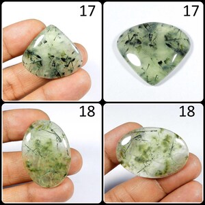 May include: Four green and black gemstone cabochons, two are triangular, two are oval. The cabochons are displayed on a hand.