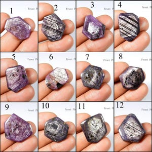 Puede incluir: Una colección de doce gemas facetadas de forma irregular. Cada gema es de un tono púrpura intenso con estrías e inclusiones internas, algunas con brillo metálico. Las gemas se muestran individualmente, mostrando sus patrones únicos.