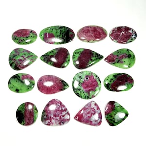 Può includere: Una collezione di pietre preziose di rubino zoisite lucide in varie forme, tra cui ovali, gocce e rotonde. Le pietre mostrano un mix di colori rosso intenso e verde vibrante, con una finitura lucida e brillante. Le pietre preziose sono su uno sfondo bianco.