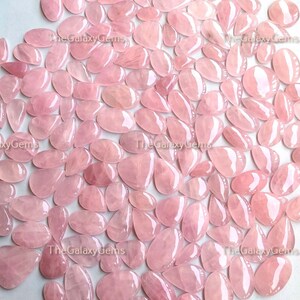 May include: A large group of pink rose quartz cabochons in a teardrop shape. The stones are smooth and polished, with a translucent appearance.