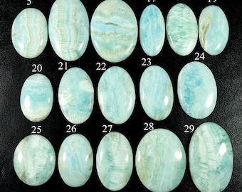 May include: A collection of fifteen polished, oval-shaped light blue and white gemstones arranged in three rows. Each stone is labelled with a white number ranging from 5 to 29, showcasing unique swirling patterns and a smooth, reflective surface finish.