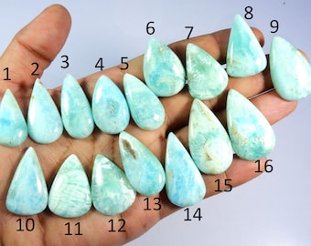 Peut inclure: Seize pierres précieuses en forme de goutte d'eau, de différentes nuances de bleu et de vert, sont présentées. Les pierres ont des motifs et des textures uniques, certaines présentant des tourbillons et des inclusions. Les pierres sont disposées dans une main.