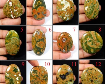 May include: A collection of twelve polished gemstones in various shapes, including oval, teardrop, and round. The stones display a mix of colors, such as green, brown, orange, and white, with unique patterns and textures. These gemstones are suitable for jewelry making.