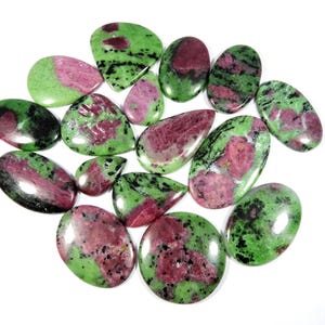 Op de afbeelding: Een verzameling van 15 groene, roze en zwarte edelsteen cabochons. De cabochons zijn allemaal druppelvormig en hebben een gladde, gepolijste afwerking.