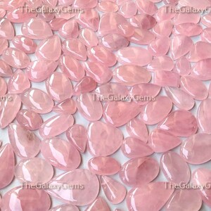 May include: A collection of pink rose quartz cabochons, each with a smooth, polished surface. The stones are various sizes and shapes, with a translucent, light pink color.
