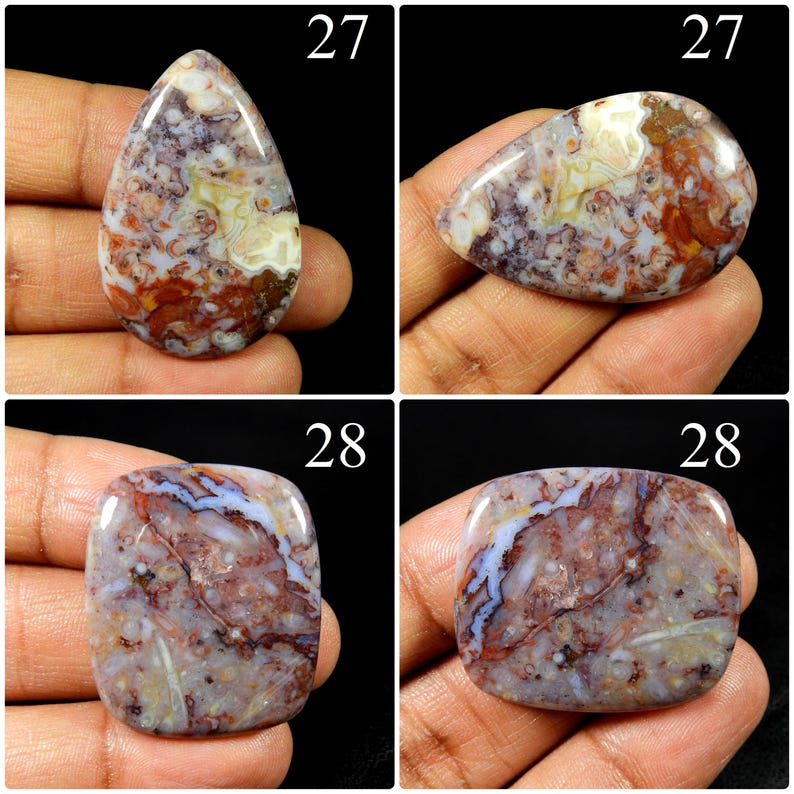 May include: Four polished cabochons of patterned agate stone. Two teardrop-shaped stones labelled 27 feature swirling red, brown, and white inclusions. Two rectangular stones labelled 28 display a mottled mix of purple, red, and white mineral patterns.