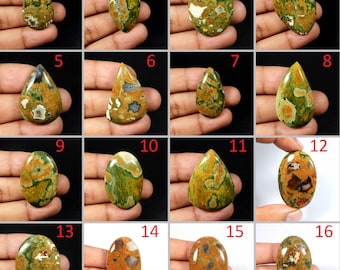 May include: Assortment of 16 green, brown, and white jasper cabochons in various shapes and sizes. The cabochons are displayed on a hand.