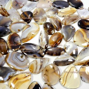 May include: A collection of agate cabochons in various shades of brown, white, and gray. The cabochons are smooth and polished, with intricate patterns of banding and inclusions. The cabochons are ideal for jewelry making, crafting, and other creative projects.