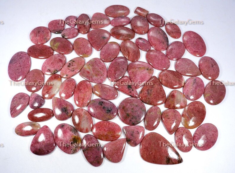 May include: A collection of 30 pink and white gemstone cabochons, with a variety of shapes and sizes. The stones are smooth and polished, with a natural, organic look.