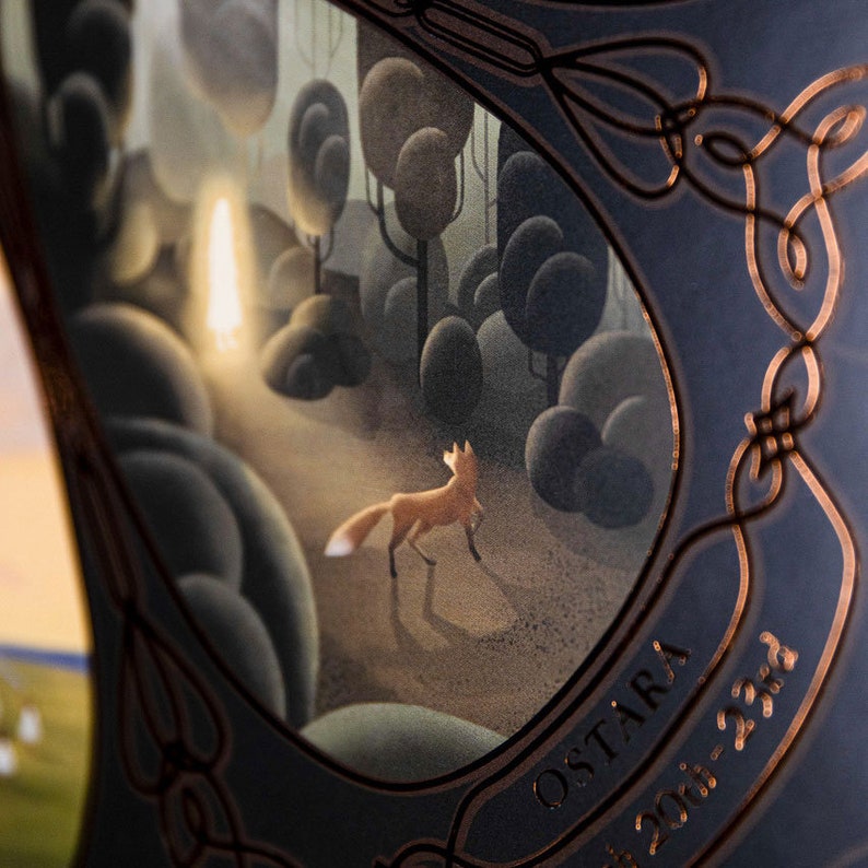 May include: A dark blue background with a copper-colored border and a circular image of a fox walking through a forest. The image is surrounded by a copper-colored design. The text "OSTARA" and "2021-23rd" are visible in the lower right corner.