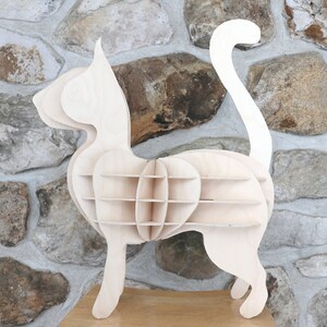 Puede incluir: Una estantería de madera con forma de gato con un acabado en madera clara. La estantería tiene varios compartimentos y está diseñada para parecer un gato de pie sobre sus cuatro patas.