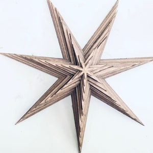 Peut inclure: Une grande étoile en bois à plusieurs couches de couleur brun clair. L'étoile est composée de plusieurs couches de bois, créant un effet tridimensionnel.