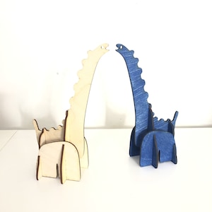 May include: Two wooden dinosaur figurines, one is natural wood color and the other is painted blue. The dinosaurs are standing upright with their necks arched back.