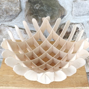 Puede incluir: Un cuenco de madera con un diseño geométrico. El cuenco está hecho de madera de color claro y tiene un patrón de cuadrícula.