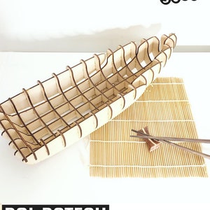 May include: A wooden boat-shaped bowl, made of interlocking pieces, is shown on a white surface. The bowl is made of light brown wood and has a natural wood finish. The bowl is empty and ready to be used. The text "BOAT BOWL" is shown in black text at the top of the image. The text "3D INTERLOCKED MODELS by Sofs" is shown in black text at the top of the image. The text "BOL BATEAU MODÈLE 3D ENCLENCHÉ" is shown in black text at the bottom of the image. The text "QUESTIONS? WWW.SOFS DESIGNS.COM" is shown in black text at the bottom of the image.