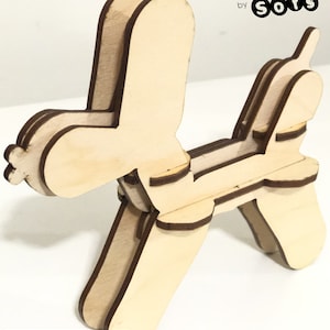 May include: A wooden 3D model of a balloon dog, assembled and ready to display. The model is made of interlocking pieces and is designed to be assembled without glue or tools. The model is painted in a natural wood color and has a brown outline.