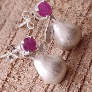 Pode incluir: Um par de brincos de prata com um design em forma de pêra. Cada brinco tem uma gema rosa engastada em uma moldura de prata.