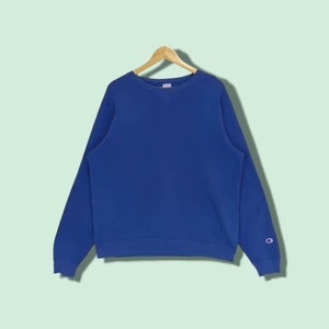 May include: A blue crew neck sweatshirt with a Champion logo on the right sleeve.