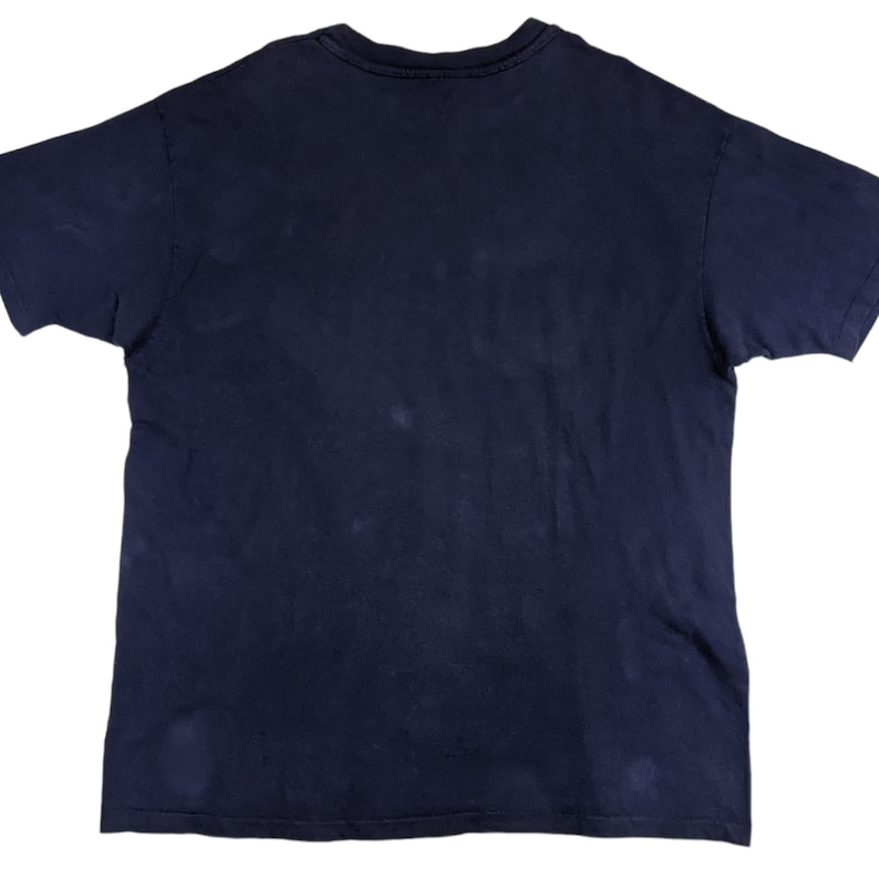 Peut inclure: Un t-shirt bleu fonc&eacute; &agrave; col rond et manches courtes. Le t-shirt est fait d'un tissu doux et confortable et a un aspect l&eacute;g&egrave;rement d&eacute;lav&eacute;.