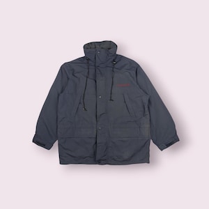 Peut inclure: Veste Columbia bleu marine avec un col montant et un logo rouge sur la poitrine. La veste a une fermeture à boutons et à glissière, deux poches avant et des poignets réglables. Conçue pour les activités de plein air.