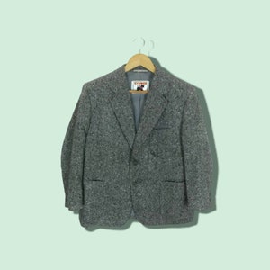 May include: A gray tweed blazer with a two-button closure and a pocket on each side. The blazer has a label that says "LYNXON" on it.
