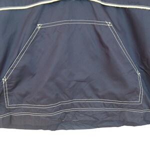 May include: A navy blue jacket with a white stitched pocket on the front.