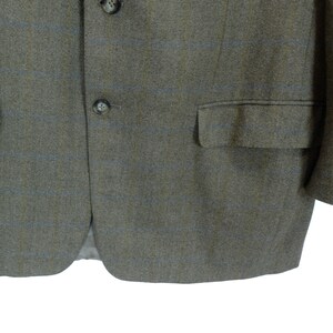 May include: A brown blazer with a subtle blue and brown plaid pattern. The blazer has two button closures and a flap pocket on the right side.