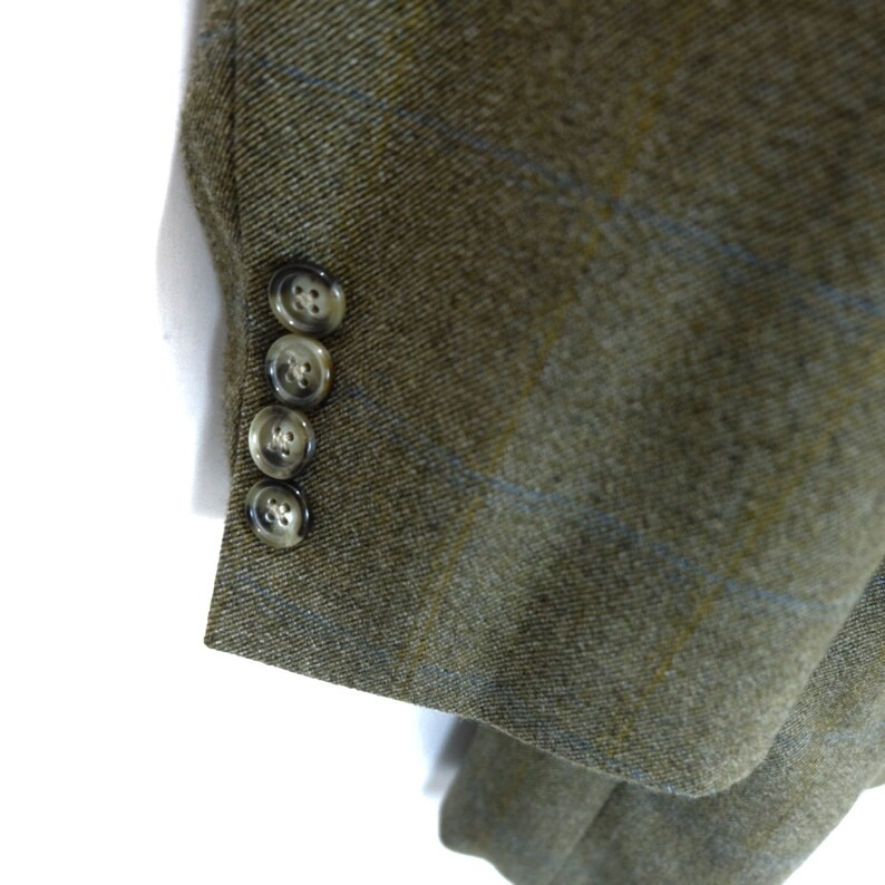 May include: Close-up of the sleeve of a brown blazer with a blue and yellow plaid pattern. The blazer has four brown buttons on the sleeve.