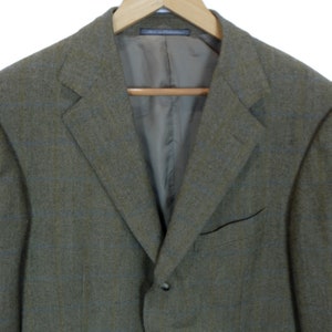 May include: A brown tweed blazer with a subtle plaid pattern. The blazer has a single button closure and a notch lapel.