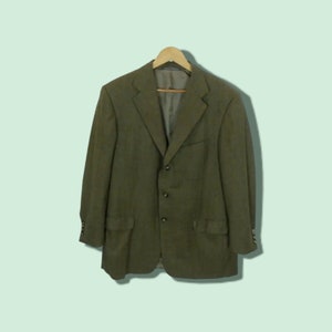 May include: A dark green blazer with a button closure and two pockets. The blazer is made of a textured fabric and has a classic style.