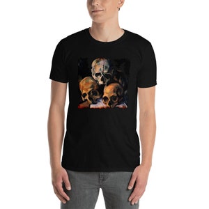 May include: Black short-sleeve t-shirt featuring a detailed, artistic rendering of several human skulls. The skulls are depicted in shades of brown, beige, and white, with a dark background. The shirt is made of a soft material.