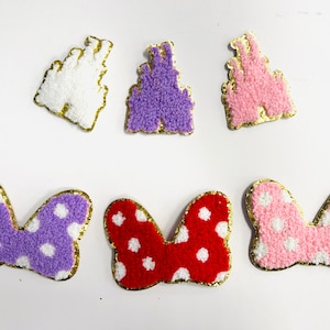 May include: Six embroidered patches in the image. Three are castle shapes in white, purple, and pink with gold trim. The other three are bow shapes in purple with white polka dots, red with white polka dots, and pink with white polka dots.