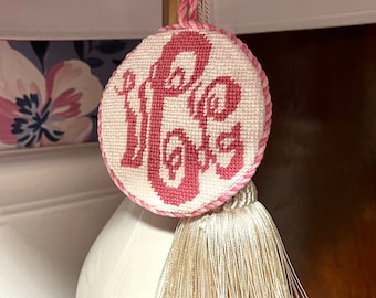 May include: A white lampshade with a pink fabric cover. A pink and white embroidered round ornament with the word "Hope" stitched in pink hangs from the lampshade with a cream tassel.