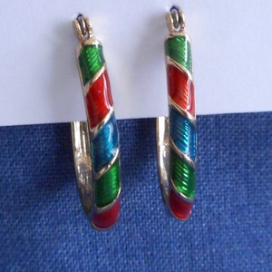 May include: A pair of gold hoop earrings with a red, green, and blue enamel design.