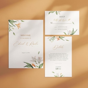 May include: A set of wedding stationery featuring floral illustrations. The design includes a welcome card, RSVP card, and details card. The cards have a white background with watercolor-style lilies and greenery. The text is in a gold script font.