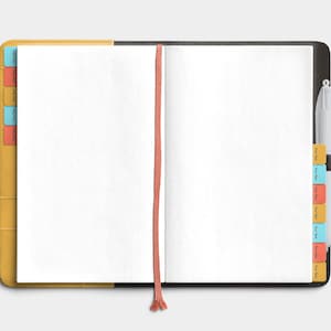 May include: Open notebook with blank white pages, a coral ribbon bookmark, and colorful tab dividers. The notebook has a yellow cover on the left and a black cover on the right, with a white pen attached.
