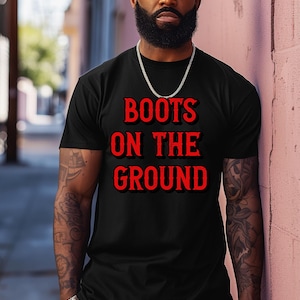 May include: A black t-shirt with the text "BOOTS ON THE GROUND" in red lettering.