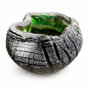 Może przedstawiać: Ręcznie wykonana ceramiczna miska z ciemnoszarym, zwęglonym zewnętrzem. Wnętrze ma żywe zielone i czerwone akcenty szkliwione. Organiczny kształt i unikalna faktura powierzchni miski tworzą rustykalną, artystyczną estetykę.
