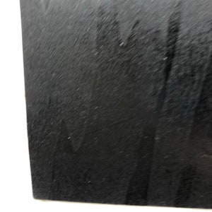 May include: A close-up of a black, textured surface. The surface appears to be made of a material like leather or suede.