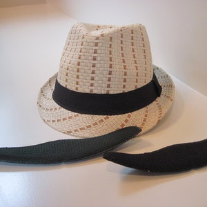 May include: A white fedora hat with a black band and two black felt hat sweatbands.