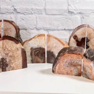 Puede incluir: Conjunto de sujetalibros de ágata en varios tonos de marrón, blanco y rosa. Los sujetalibros están hechos de rebanadas de ágata natural y tienen una forma única y orgánica.