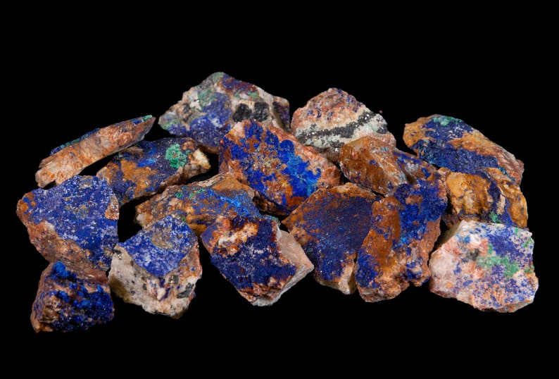 May include: A collection of rough, raw azurite stones with a mix of blue, brown, and green hues. The stones are irregular in shape and have a natural, unpolished finish.