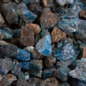 May include: A close-up of a pile of blue and gray stones. The stones are rough and have a variety of shapes and sizes.