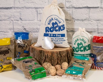 May include: Assortment of Kids Love Rocks bags containing various types of rocks and minerals. The bags are labeled with the names of the rocks and minerals, such as "Gemstone Bag", "Assaver's Bag", and "Patriot Bag".