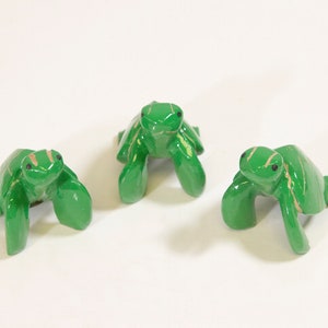 May include: Three green ceramic turtle figurines with black eyes. The turtles are in different poses, with their heads facing forward, to the side, and up.